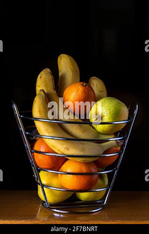 Ancora vita di cesto di frutta con banane, mele e arance con fondo nero. Italia, Europa Foto Stock