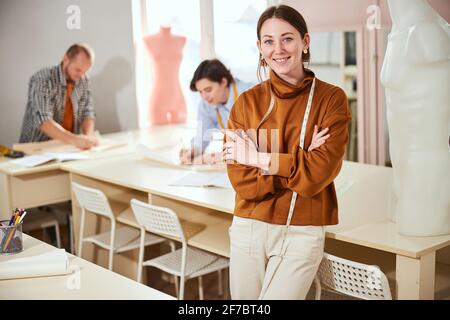 Stilista di moda sorridente davanti a due colleghi di lavoro Foto Stock