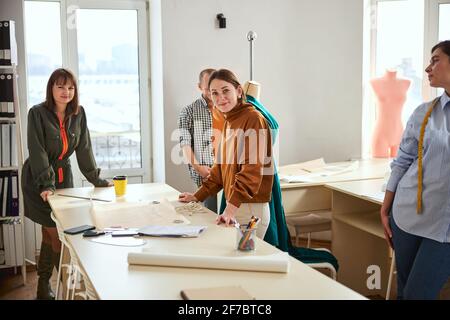 Due designer di abiti in piedi vicino al tavolo con strumenti di sartoria Foto Stock