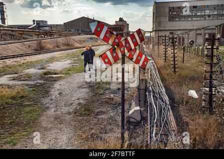 Obsoleto impianto di estrazione e trasformazione sovietico. Segnale ferroviario rosso e lavoratori. Foto Stock