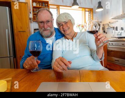 COVID-19 resta connesso e speranza concetto. Buon giovane coppia con il vino che chiama gli amici sul laptop o chiacchierando online con la famiglia per festeggiare eas Foto Stock