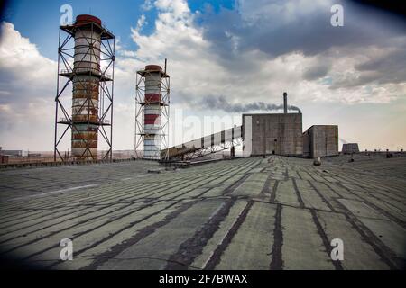 Obsoleto impianto di estrazione e trasformazione sovietico. Pile di fumo sul tetto e edificio industriale sullo sfondo. Foto Stock