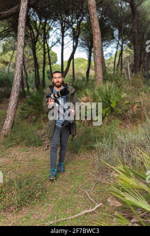 Fotografo che cammina con la sua fotocamera DSLR in campagna. Foto Stock