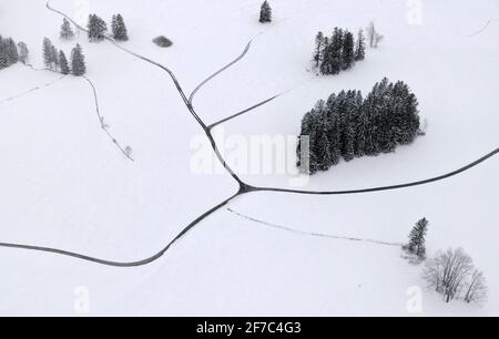 Bernbeuren, Germania. 06 Aprile 2021. Sentieri e alberi si distinguono nel paesaggio coperto di neve fresca veduta aerea con un drone). Credit: Karl-Josef Hildenbrand/dpa/Alamy Live News Foto Stock
