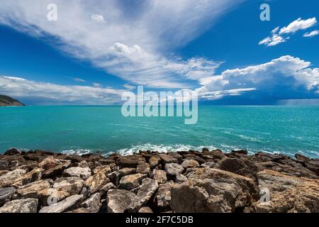 Spiaggia rocciosa e bella stagione verde con nubi tempesta all'orizzonte. Tellaro, Golfo di la Spezia, comune di Lerici, Liguria, Italia, UE Foto Stock