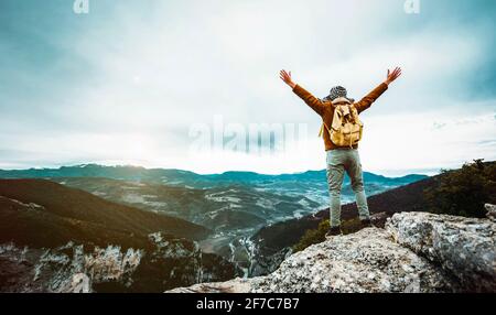 Escursionista con zaino che solleva le braccia sulla cima di La montagna - uomo di successo che celebra la vittoria Foto Stock