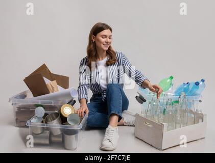 Ritratto di giovane donna seduto tra i contenitori con spazzatura ordinata Foto Stock