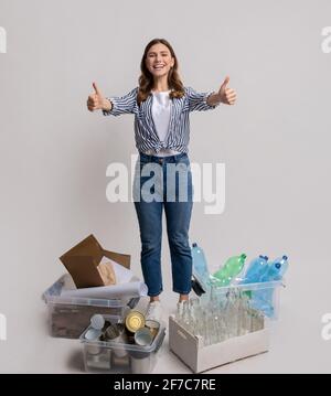 Concetto di riciclaggio dei materiali. Happy Woman in piedi accanto a contenitori con diversi rifiuti Foto Stock