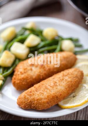 Filetto di pesce impanato con patate e fagioli verdi. Foto Stock