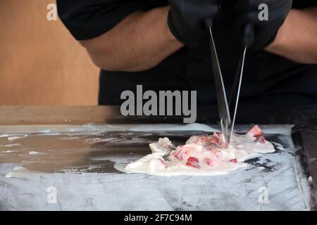 Uomo che prepara il gelato fritto con la fragola. Estate alla moda fresco sfondo di dessert ghiacciato. Foto Stock