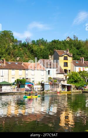 NEMOURS, FRANCIA - 7 LUGLIO 2019: Canoa in coppia sul fiume Loing e case pittoresche lungo l'acqua. Nemours è una città medievale a Seine-et Foto Stock