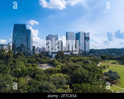 Splendida vista aerea di edifici aziendali in vetro, alberi del parco Parque do Povo e skyline di São Paulo nella soleggiata giornata estiva. Foto Stock