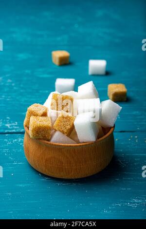 Cubetti di zucchero dolce in un piccolo piatto di legno. Alcuni grammi di zucchero. Cubetti di zucchero di canna Foto Stock