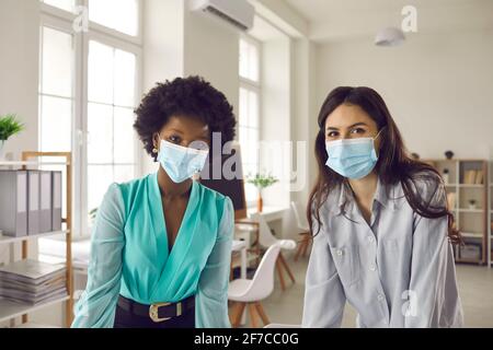 Ritratto dei colleghi aziendali in maschere di fronte in ufficio durante pandemia di coronavirus Foto Stock