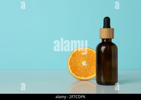 Flacone contagocce con olio e arancione su sfondo blu Foto Stock