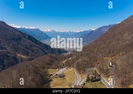 Vista aerea della Valle Morobbia, paesaggio invernale in una giornata di sole con neve sulle montagne. In fondo alla valle si trova il Magadino Foto Stock