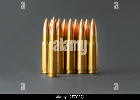 Punti elenco su sfondo grigio. Cartucce calibro 7.62 per il closeup del fucile d'assalto Kalashnikov. Messa a fuoco selettiva in primo piano. Foto Stock