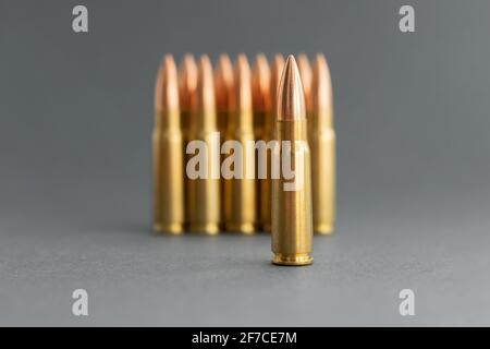 Punti elenco su sfondo grigio. Cartucce calibro 7.62 per il closeup del fucile d'assalto Kalashnikov. Messa a fuoco selettiva in primo piano. Foto Stock