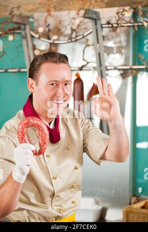 Lavorare in un macellaio - un macellaio con salsiccia Foto Stock