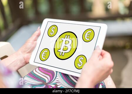 Il concetto di Bitcoin mostrato su un tablet tenuto da una donna Foto Stock