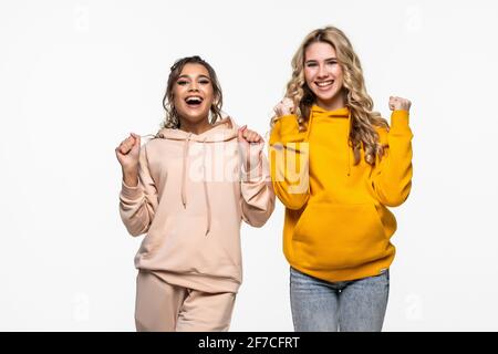 Due giovani donne che fanno il gesto vincitore celebrando isolato su bianco sfondo Foto Stock