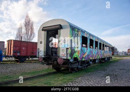 01 aprile 2021, Sassonia-Anhalt, Magdeburgo: Nel Porto della Scienza c'è un carro ferroviario spruzzato di graffiti. Dietro di esso, si può vedere un treno merci scartato. L'associazione 'Magdeburger Eisenbahnfreunde' si è posta l'obiettivo di ripristinare e quindi preservare tali carri e vecchie locomotive. Foto: Stephan Schulz/dpa-Zentralbild/ZB Foto Stock