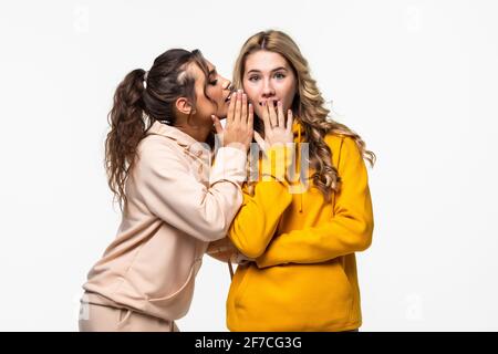 Donna raccontare gossip alla sua fidanzata su sfondo grigio Foto Stock
