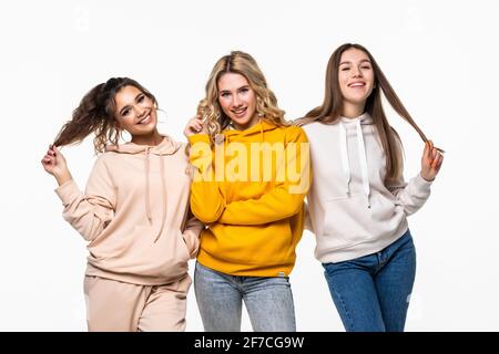 tre amici donne che si levano in piedi insieme e guardano la caemra su sfondo bianco Foto Stock