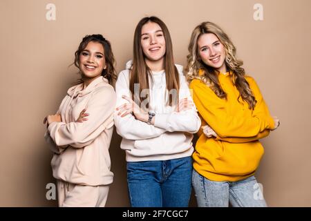 Tre amici donne in piedi insieme su sfondo beige Foto Stock