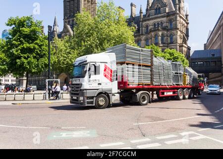 Un camion Mercedes-Benz Actros 1844 trasporta un rimorchio piatto articolato che trasporta le barriere di controllo della folla portatili lontano da Albert Square, Manchester. Foto Stock