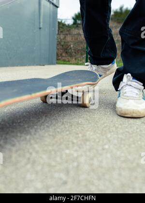 Primo piano di uno skateboard con una persona sconosciuta in piedi dietro di esso. Skateboard concetto di stile di vita sano Foto Stock