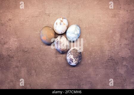 Happy Easter uova con effetto marmo in pietra dipinta con fondo in cemento grigio naturale con spazio vuoto per il testo. Vista dall'alto, posa piatta Foto Stock