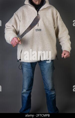 Un uomo che tiene un machete in modo minaccioso Foto Stock