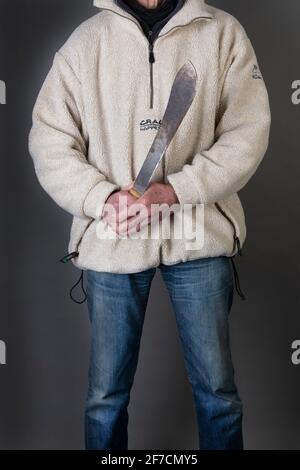 Un uomo che tiene un machete in modo minaccioso Foto Stock