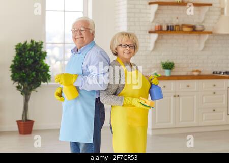 Felice coppia senior sorridente in piedi indietro nel cucina dopo aver pulito la loro casa Foto Stock