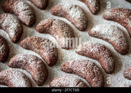 Teglia da forno con biscotti fatti in casa con nocciole a mezzaluna di cioccolato e polvere di zucchero su fondo di legno marrone. Vista dall'alto. Messa a fuoco morbida Foto Stock