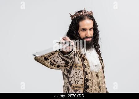 re ispanico in abiti medievali e corona con spada sfocata isolato su bianco Foto Stock
