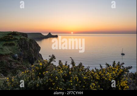 Testa di verme Rhossili Bay al tramonto e una barca singola, penisola di Gower, Galles del Sud, Regno Unito Foto Stock