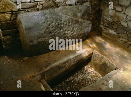 Il cist sepolcrale & il capstone decorati con due assi, & i cupmarks & assi all'interno di Nether Largie North Bronze Age round cairn, Kilmartin Glen, Scozia, Regno Unito. Foto Stock