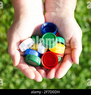 tappi colorati in plastica nelle mani delle donne. il concetto di ecologia Foto Stock