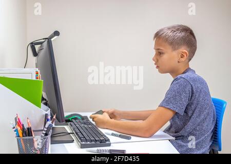 Teenage boy distracting da lezione online o compiti e giocare a videogiochi, telefono a scorrimento a casa Foto Stock