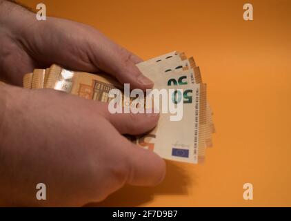 Uomo che conta denaro con le mani, concetto di economia, allocazione di denaro su sfondo giallo Foto Stock