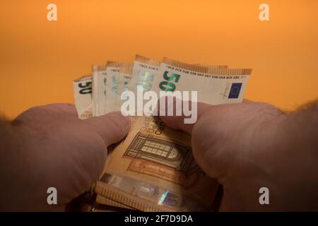 Uomo che conta denaro con le mani, concetto di economia, allocazione di denaro su sfondo giallo Foto Stock