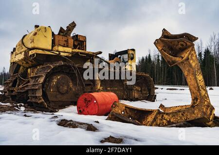 Un bulldozer giallo grande vecchio smontato difettoso. Trattore cingolato rotto in forma smontata con il motore smontato. Foto Stock