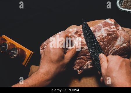 Carne cruda, collo di maiale, il cuoco prepara la carne per la marinatura, taglia il lardo.2020 Foto Stock