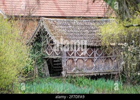 Antico fienile in legno con ornato modello in legno su palafitte sopra stagno Foto Stock