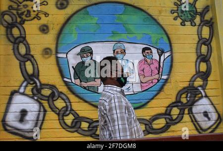 Mumbai, India. 06 Aprile 2021. Un uomo che indossa una maschera protettiva passa accanto a un graffiti dipinto per creare consapevolezza circa la malattia del virus corona a Mumbai.a causa dell'aumento dei casi di coronavirus nello stato di Maharashtra, il governo ha imposto il coprifuoco notturno dalle 20:00 alle 7:00 per frenare la diffusione del coronavirus. (Foto di Ashish Vaishnav/SOPA Images/Sipa USA) Credit: Sipa USA/Alamy Live News Foto Stock