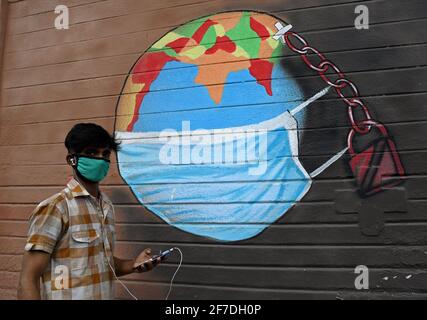 Mumbai, India. 06 Aprile 2021. Un uomo che indossa una maschera protettiva passa accanto a un graffiti dipinto per creare consapevolezza circa la malattia del virus corona a Mumbai.a causa dell'aumento dei casi di coronavirus nello stato di Maharashtra, il governo ha imposto il coprifuoco notturno dalle 20:00 alle 7:00 per frenare la diffusione del coronavirus. (Foto di Ashish Vaishnav/SOPA Images/Sipa USA) Credit: Sipa USA/Alamy Live News Foto Stock