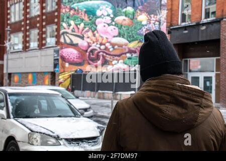 Una giovane donna in abbigliamento invernale, capovolta, ammirando un murale a Londra, Ontario, Canada, febbraio 10 2021. Foto Stock