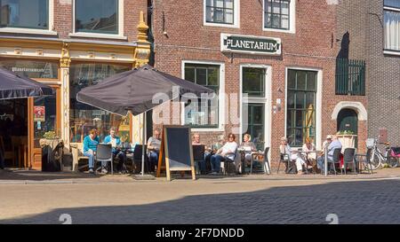 La gente siede su una terrazza di fronte al planetario Eise Eisinga del XVIII secolo a Franeker in una giornata di sole. Foto Stock
